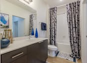 Thumbnail 10 of 25 - A bathroom with a toilet, sink, and shower curtain.