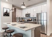 Thumbnail 12 of 40 - A modern kitchen with a large island and stainless steel appliances.