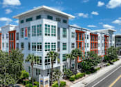 Thumbnail 38 of 40 - A white building with red doors and windows is surrounded by trees.