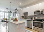 Thumbnail 11 of 40 - A kitchen with white cabinets and a white island.