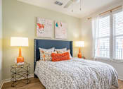 Thumbnail 18 of 40 - A bedroom with a bed, two lamps, and a painting on the wall.