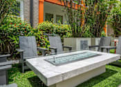 Thumbnail 33 of 40 - A modern outdoor seating area with a glass table and grey chairs.