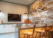 Thumbnail 7 of 40 - A kitchen with a stone wall and a countertop with chairs.