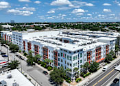 Thumbnail 39 of 40 - A large multi-story building with a parking lot in front.