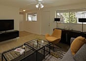 Thumbnail 10 of 49 - A living room with a television, a chair, and a coffee table.