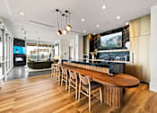 Thumbnail 66 of 72 - A modern kitchen with a long wooden island and chairs.