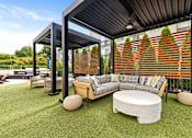 Thumbnail 55 of 72 - A modern outdoor seating area with a wooden bench and a white cushion.