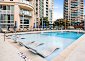 Thumbnail 1 of 72 - Luxury Apartments in Buckhead, GA, With In-Unit Washer and Dryer - The Huntley - Resort-Style Swimming Pool With In-Water Lounge Chairs, Sundeck Seating, Blue Umbrellas, and High-Rise Views.