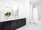Thumbnail 46 of 80 - A bathroom with a white sink and black cabinets.