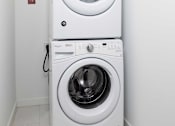 Thumbnail 25 of 80 - A white washing machine and dryer in a small room.