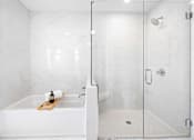 Thumbnail 29 of 80 - A white bathroom with a marble wall and a glass shower door.