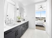 Thumbnail 27 of 80 - A bathroom with a black vanity and a white ceiling fan.