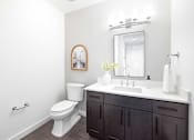 Thumbnail 75 of 80 - A white toilet sits next to a sink in a bathroom.