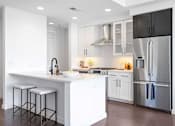 Thumbnail 40 of 80 - Luxury Apartments Near Lenox Square Mall In Buckhead, GA - The Huntley - Kitchen With Luxurious Tuscany and Rocksalt Quartz Counter-Tops, Stainless-Steel Appliances, Genuine Hardwood Floors, Kitchen Island, And White Cabinets.