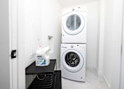 Thumbnail 45 of 80 - A white washing machine is in a small laundry room.