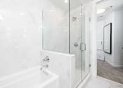 Thumbnail 52 of 80 - A white marble bathroom with a glass shower door.