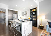 Thumbnail 33 of 80 - A modern kitchen with a white island and dark wood floors.