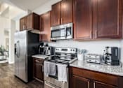 Thumbnail 17 of 26 - A modern kitchen with dark wood cabinets and stainless steel appliances.