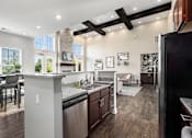 Thumbnail 18 of 26 - A modern kitchen with dark wood floors and stainless steel appliances.
