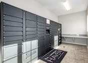 Thumbnail 21 of 26 - A room with a row of black lockers on the wall and a bench.