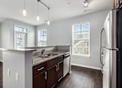 Thumbnail 9 of 26 - A kitchen with a refrigerator, sink, and cabinets.