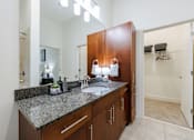 Thumbnail 20 of 28 - A bathroom with a sink, mirror, and wooden cabinets.