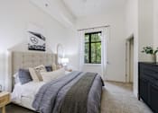 Thumbnail 19 of 28 - A bedroom with a large bed and a window with a view of trees.