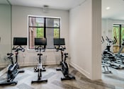 Thumbnail 11 of 28 - A room with a row of stationary bikes.