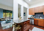 Thumbnail 14 of 28 - A kitchen with wooden cabinets and a marble countertop.