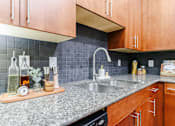 Thumbnail 13 of 28 - A kitchen with a granite countertop and wooden cabinets.
