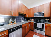 Thumbnail 12 of 28 - A kitchen with wooden cabinets and a granite counter top.