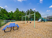 Thumbnail 27 of 28 - A playground with a blue picnic table and a green swing set.