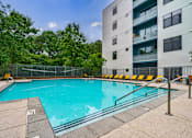 Thumbnail 1 of 28 - A swimming pool surrounded by a metal fence and yellow chairs.