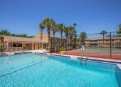 Thumbnail 4 of 38 - a swimming pool with a tennis court and a building with palm trees