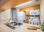 Thumbnail 14 of 30 - A kitchen with a stainless steel sink and a white refrigerator.