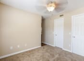 Thumbnail 22 of 38 - an empty living room with two doors and a ceiling fan