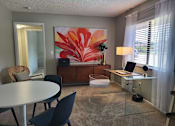 Thumbnail 21 of 31 - A room with a table, chairs, and a painting of a flower  at Waterview at Rocky Point, Florida