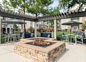 Thumbnail 19 of 30 - a patio with a fire pit and tables with chairs and umbrellas