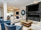 Thumbnail 3 of 34 - A modern living room with a fireplace and a large TV.