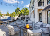 Thumbnail 16 of 34 - A patio with a fire pit and chairs.