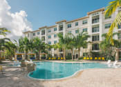 Thumbnail 16 of 35 - a swimming pool in front of a hotel with palm trees