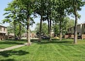Thumbnail 3 of 27 - A grassy area with trees and houses in the background.