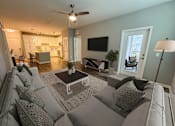 Thumbnail 24 of 31 - A living room with a grey couch and a coffee table.