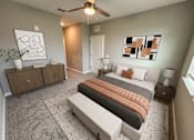 Thumbnail 23 of 31 - A bedroom with a bed, a bench, and a ceiling fan.
