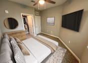 Thumbnail 22 of 31 - A bedroom with a bed, a couch, a mirror, and a ceiling fan.