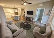 Thumbnail 15 of 31 - A living room with a grey couch and a green pillow.