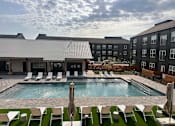 Thumbnail 1 of 15 - an outdoor pool with chairs and a building