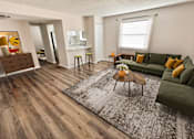 Thumbnail 17 of 38 - A living room with a green couch and a wooden floor.