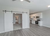 Thumbnail 16 of 48 - A room with a sliding door and a kitchen area in the background.