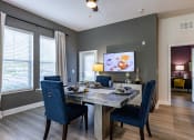 Thumbnail 18 of 35 - Dog-Friendly Apartments in Altamonte Springs, FL - Nine12 Gateway - Dining Area with Vinyl Plank Flooring, Dining Table, Chairs, Storage Cabinet, Wall-Mounted TV, Ceiling Fan, and Large Windows.